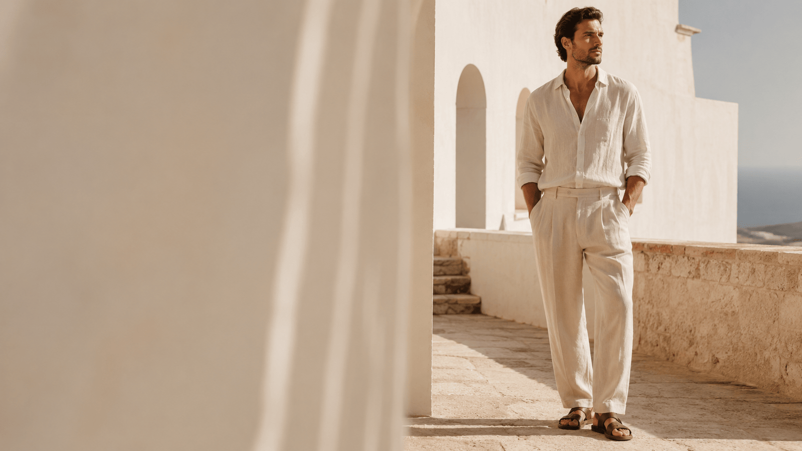 Summer Collection For Women — man in ivory linen tailoring on a sunlit Mediterranean terrace, quiet luxury editorial